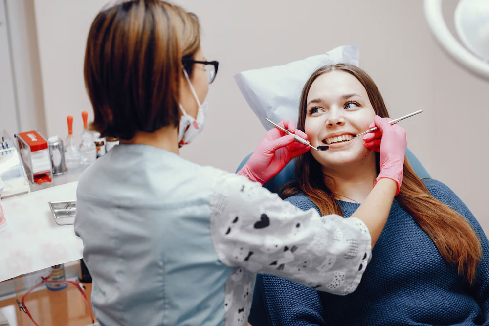 Dentist making professional teeth cleaning withb cotton female young-patient  West Hollywood, CA 